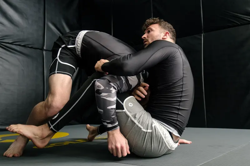 Two athletes training Brazilian jiu jitsu on the mat