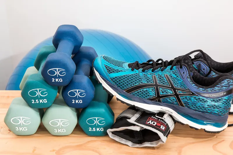 Dumbbells, a pilates ball and a pair of training shoes on a bench